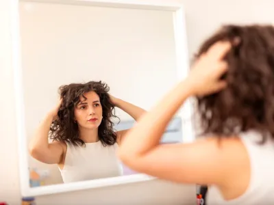 donna allo specchio mentre si tocca i capelli